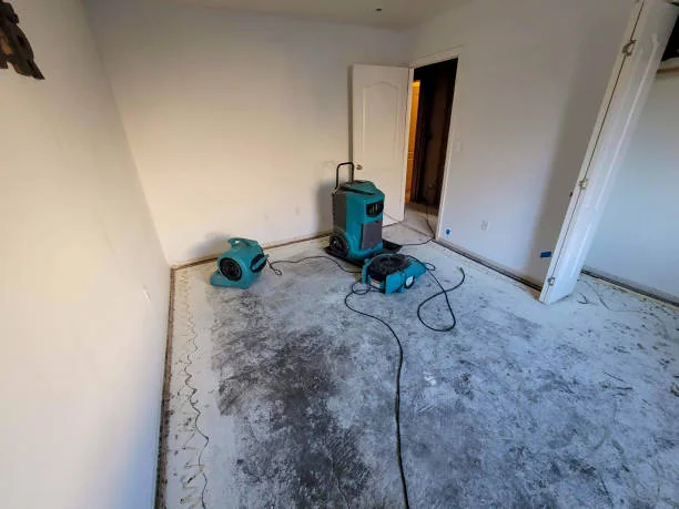 Bedroom with wet flooring removed and drying equipment running on the bare subfloor